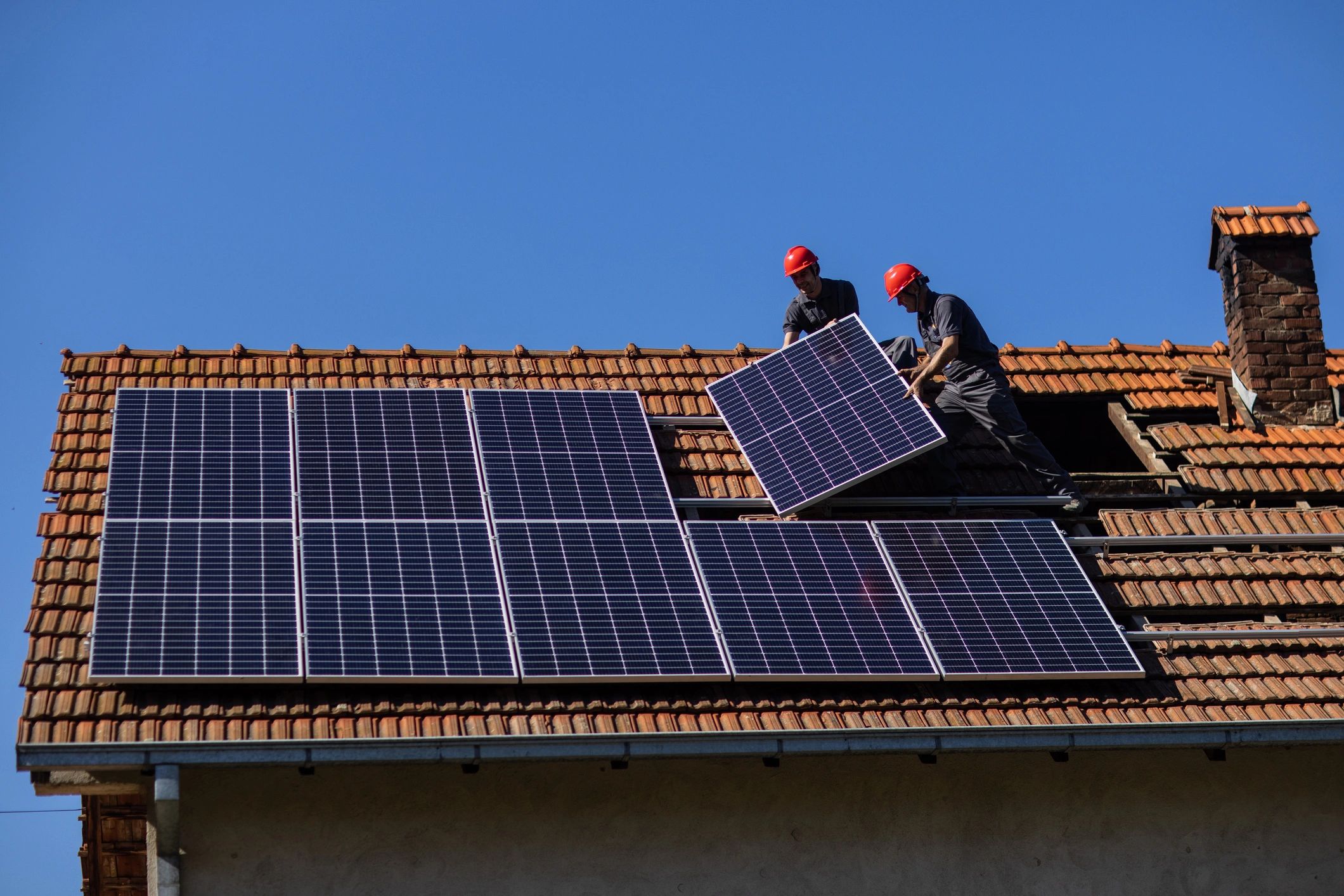Illustrative view of solar panel installers working on a home roof